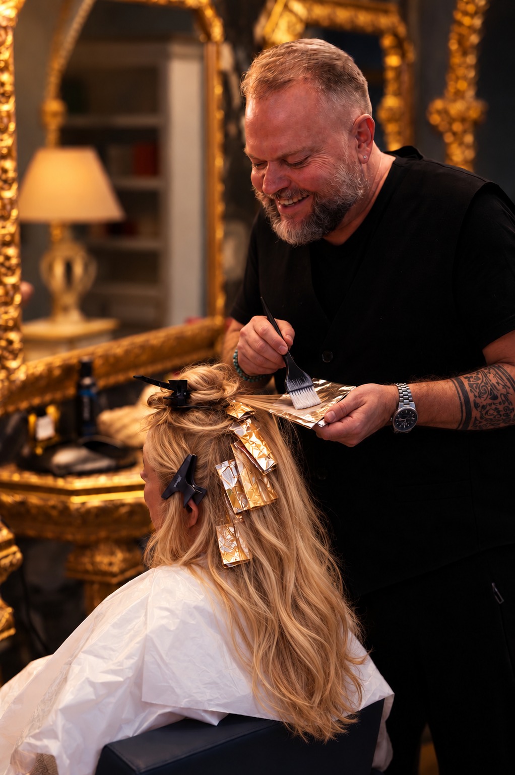 Hair stylist al lavoro sulla colorazione dei capelli lunghi di una cliente bionda nel salone Hammam Kenz